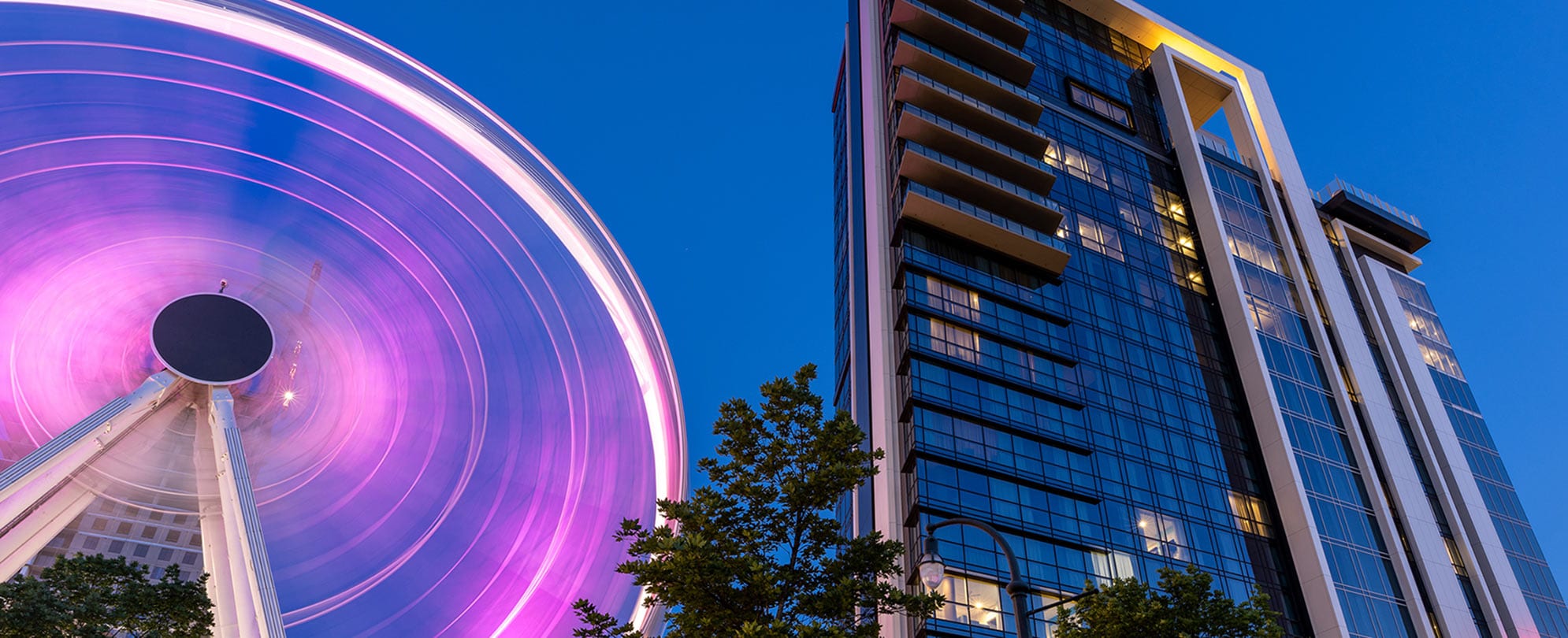 A new, high-rise Wyndham Destinations timeshare resort in Atlanta, GA and the Atlanta Ferris wheel shown from the ground.