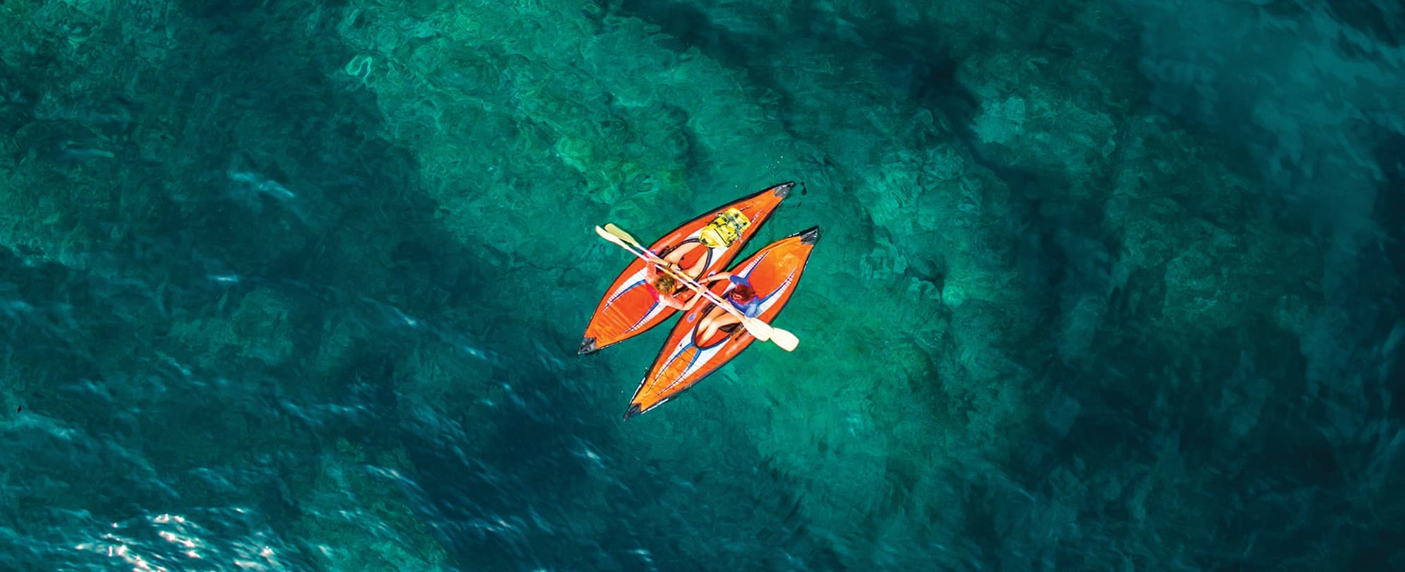 Two kayakers floating together in the middle of a body of water 
